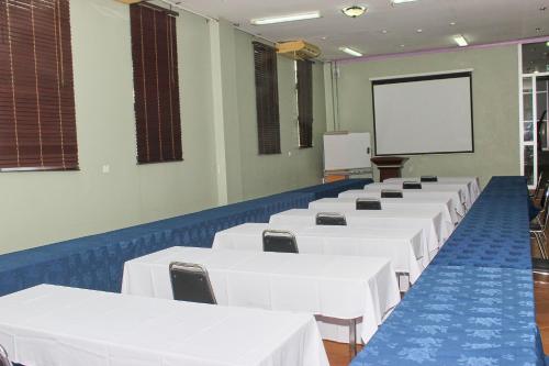 una stanza con tavoli e sedie bianchi e uno schermo di The Congress Hotel a Accra