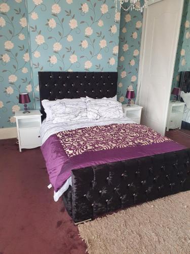 een slaapkamer met een bed met paarse lakens en bloemenbehang bij Southfield lodge in Middlesbrough