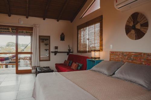 a bedroom with a bed and a red couch at Pousada Canto do Rosa in Praia do Rosa