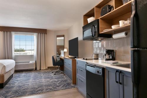 a kitchen in a hotel room with a bed at Candlewood Suites Fayetteville Fort Bragg by IHG in Fayetteville