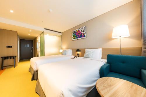 a hotel room with two beds and a blue couch at Howard Johnson by Wyndham Incheon Airport in Incheon