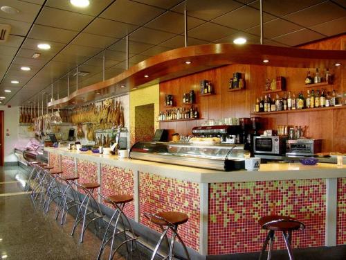 un restaurant avec comptoir et tabourets de bar dans l'établissement Complejo El Carrascal, à Muñana