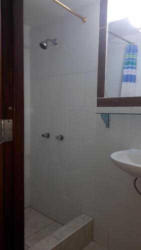 a white bathroom with a shower and a sink at Hostal Villa Brisa in Ballenita
