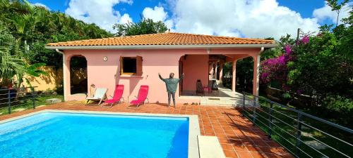 um homem parado em frente a uma casa com uma piscina em Martinique hostel em Sainte-Luce