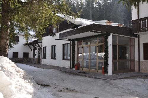 a building with glass doors in the snow at Casa Alpina Dobbiaco in Dobbiaco
