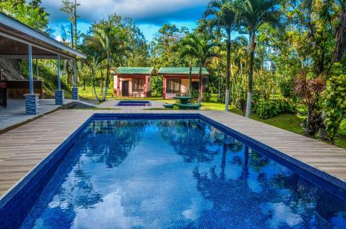 a swimming pool with a wooden deck and a house at Lumbres Arenal in Fortuna
