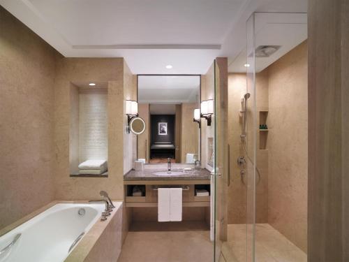 a bathroom with a tub and a sink and a mirror at Shangri-La Qufu in Qufu