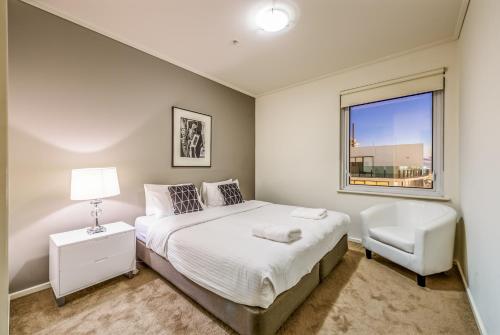 a bedroom with a bed and a chair and a window at Exclusive Stays - The Centurion in Melbourne