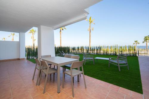 a patio with a table and chairs and palm trees at Linara in San Juan de los Terreros
