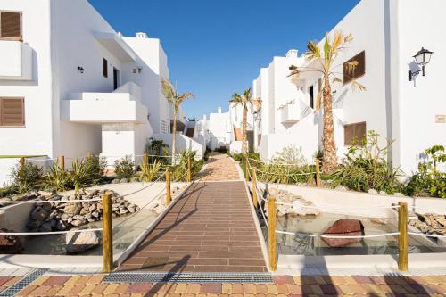 a path between white buildings with palm trees at Linara in San Juan de los Terreros