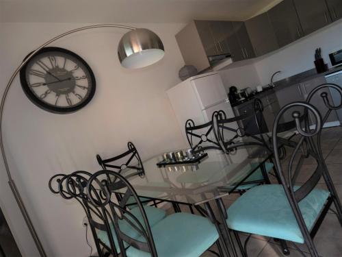a dining room with a glass table and a clock on the wall at Palm Beach in Le Gosier