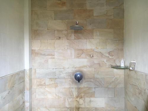 a shower with a stone wall in a bathroom at Amed Sunset Beach in Amed