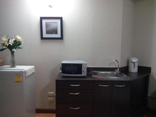 a kitchen with a sink and a microwave and a refrigerator at Asia Don Mueang Bangkok Condominium in Thung Si Kan