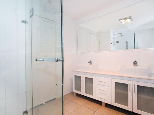 a bathroom with two sinks and a glass shower at Mayfield 23 in Alexandra Headland