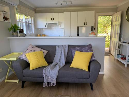 a living room with a gray couch with yellow pillows at Stephanie’s Country Cottages in Drummond