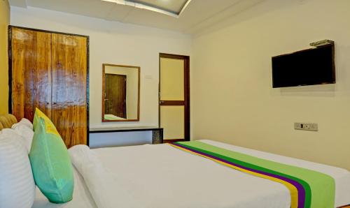 a bedroom with a white bed and a flat screen tv at Hotel Lake Paradise Mahabaleshwar in Mahabaleshwar