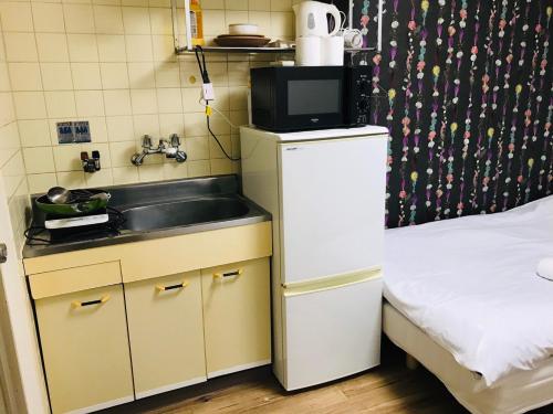 大阪市にあるEX Tenjinnomori Apartment 104のシンクと冷蔵庫のある小さなキッチン