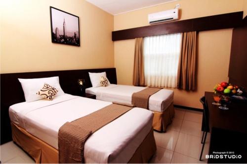 a hotel room with two beds and a window at Pondok Keluarga Osamaliki in Salatiga