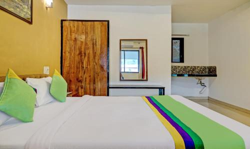 a bedroom with a large white bed with green pillows at Hotel Lake Paradise Mahabaleshwar in Mahabaleshwar