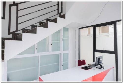 an office with a staircase and a desk with a laptop at RedDoorz near Kota Tua 2 in Jakarta