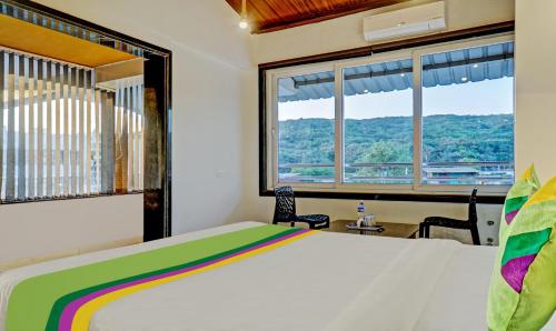 a bedroom with a bed and two windows at Hotel Lake Paradise Mahabaleshwar in Mahabaleshwar