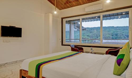 a bedroom with a bed with a window and a tv at Hotel Lake Paradise Mahabaleshwar in Mahabaleshwar