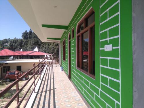 a green wall of a building with a window at Maa Anand Mayee Guest House in Panuānaula