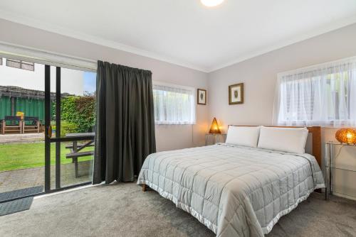 a bedroom with a bed and a large window at Pomare Cottage - Rotorua Holiday Home in Koutu
