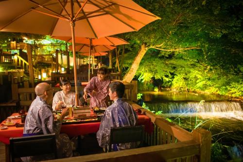 a group of people sitting at a table near a river at Harataki in Aizuwakamatsu