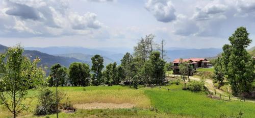 a house in the middle of a field with trees at Maa Anand Mayee Guest House in Panuānaula