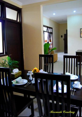 a dining room with a table and chairs with plates on it at Roemah Canting Homestay in Yogyakarta