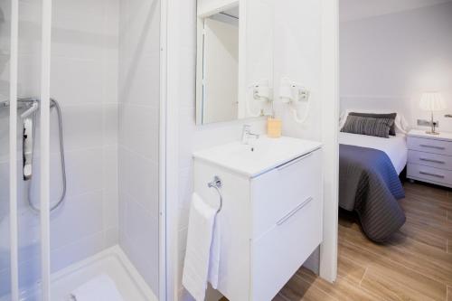 a white bathroom with a sink and a shower at El Niu de Escaldes in Escaldes-Engordany