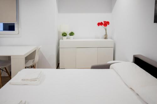 a white bedroom with a bed and a desk at El Niu de Escaldes in Escaldes-Engordany