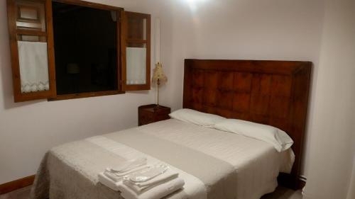 a bedroom with a bed with white sheets and a window at Las Casitas de Papel in Ampudia