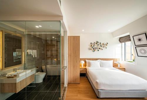 a bedroom with a large bed and a bathroom at Ann Hotel & Spa Khem Beach PQ in Phú Quốc