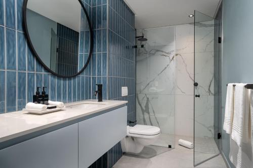 a bathroom with a sink and a toilet and a mirror at Home Suite Hotels De Waterkant in Cape Town