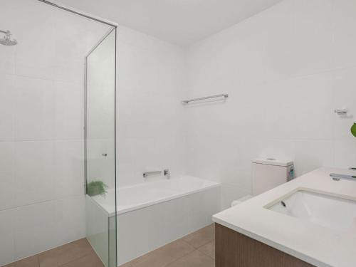 a bathroom with a glass shower and a sink at Ebbtide 38 On The Beach in Forster