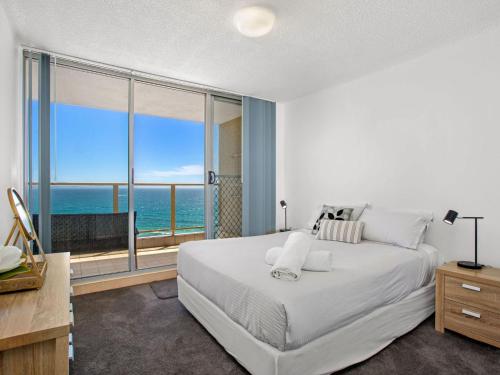 a bedroom with a large bed with a view of the ocean at Ebbtide 38 On The Beach in Forster