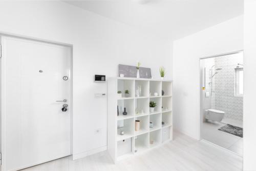 a white bathroom with white shelves and a door at REEAS APARTAMENT 13 in Chişoda