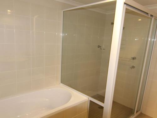een badkamer met een douche en een wit bad bij Twin Pines 301 CBD Location in Forster