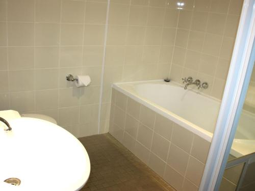 a bathroom with a tub and a toilet and a sink at Twin Pines 401 CBD Location in Forster