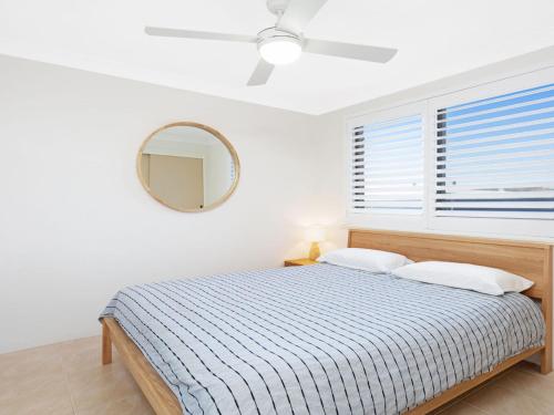 a bedroom with a bed and a mirror and a window at Surfspray 2 Pebbly Beach in Forster