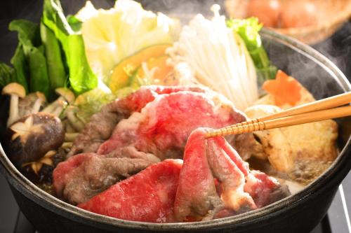 a bowl of food with meat and vegetables with chopsticks at Konjakutei in Aizuwakamatsu