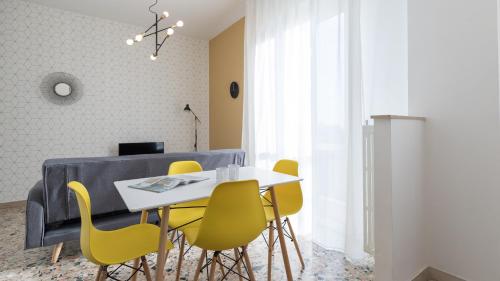 a dining room with a table and yellow chairs at Italianway - Quarnaro 2 in Monza