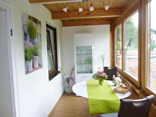 a dining room with a green table and some windows at Ferienappartement in der Wolfsgrube-Rambichler in Chieming