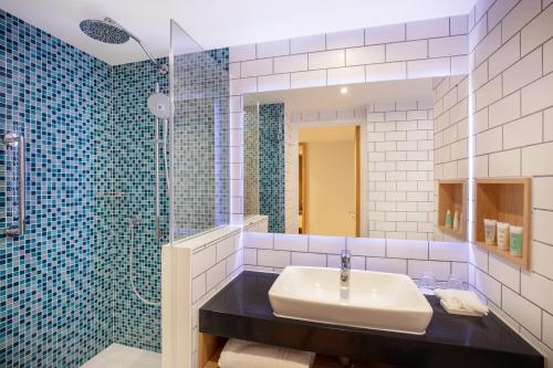 a bathroom with a sink and a shower and a mirror at Holiday Inn London Heathrow - Bath Road, an IHG Hotel in Hillingdon