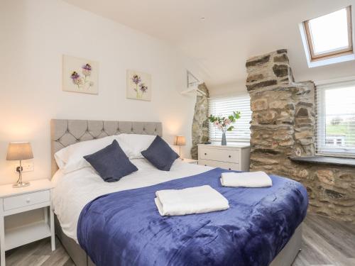 a bedroom with a large bed and a stone wall at Drovers Barn in Corwen