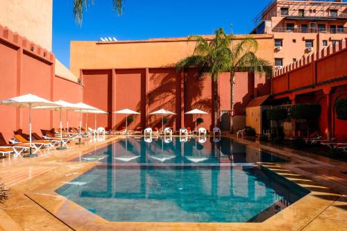 Diwane Hotel & Spa Marrakech في مراكش: مسبح وكراسي ومظلات بجانب مبنى