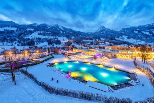 a resort with a pool in the snow at night at Appartements MAYR inklusive ganzjährig GRATIS Zugang zur ALPENTHERME und im SOMMER kostenlose Bergbahnnutzung in Bad Hofgastein
