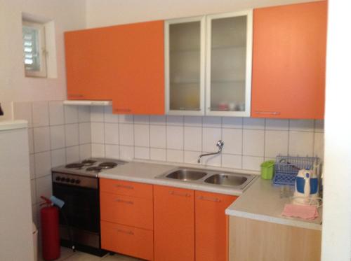 cocina con armarios de color naranja y fregadero en Apartments Diana, en Primošten